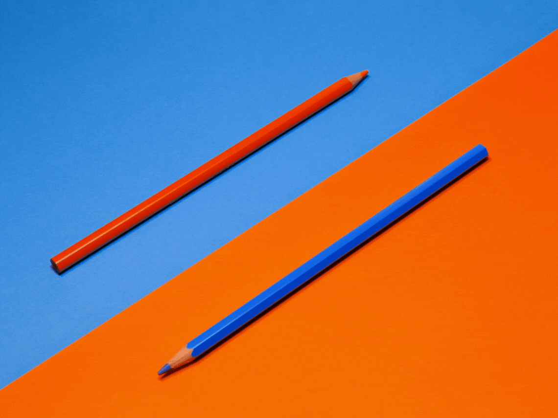 two colored pencils on an orange and blue background, with animated hexagons fading in and out.